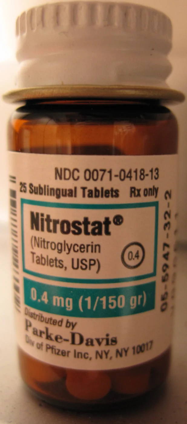 Braunes Glasfläschchen mit weißem Schraubdeckel; Etikett: 25 Sublingualtabletten Nitroglycerin 0,4 mg; orangefarbene Tabletten am Boden