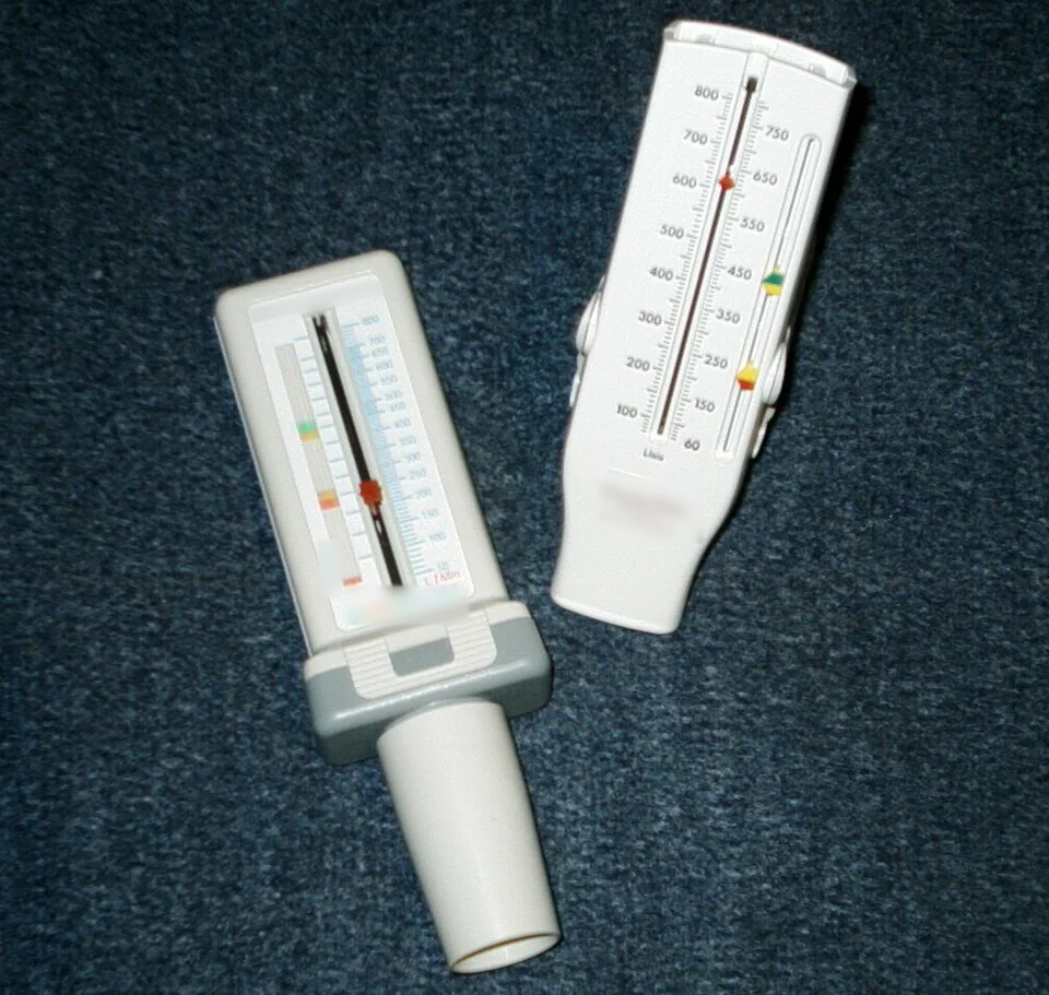 Zwei mechanische Peak-Flow-Meter mit Mundstück, Schleppzeiger und Skala in Litern pro Minute; an den Skalen sitzen verschiebbare farbige Markierungen.